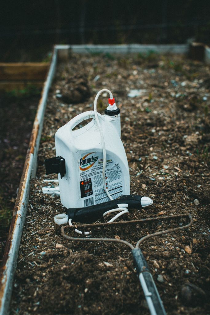 Botella del producto Roundup sobre un pequeño terreno.